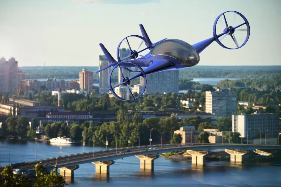 3D rendering of blue flying car over a cityscape and buildings, a river, and bridges in the background.